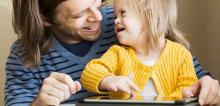 Padre con una niña con discapacidad usando una tablet.