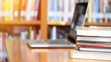 Portátil y libros por encima de una mesa en una biblioteca.