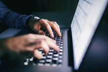Manos de un hombre sobre el teclado de un portátil.