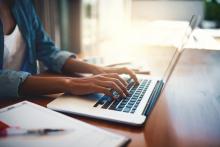Manos de una mujer sobre el teclado de un portátil.