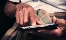 Una persona mayor utiliza una tableta con sus manos.