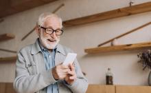 Un home maior utiliza riseiro o seu teléfono móbil.
