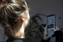 Moza de costas usando un smartphone.