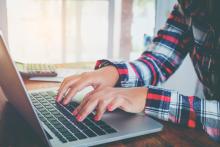 Manos de una mujer sobre el teclado de un portátil.