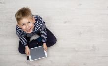 Un niño sentado en el suelo utiliza una tableta.