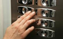 Unha persoa le as indicacións en braille nun ascensor.