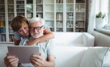 Una pareja de personas mayores utiliza una tableta en su salón.