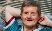 Fotografía de un hombre con síndrome de Down sonriente.